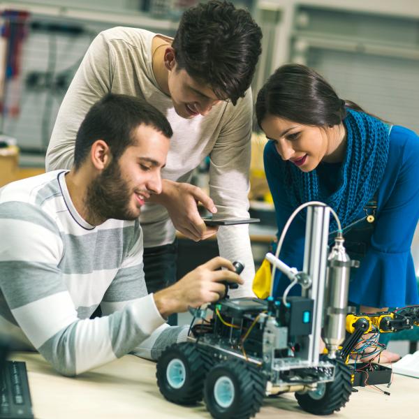 Young students of robotics preparing robot for testing in workshop