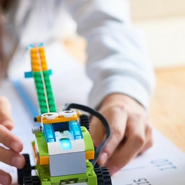 Image of child playing with a Lego robot, next to an i-pad.
