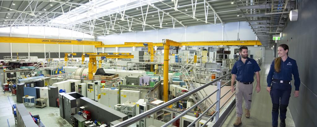 Image of two people walking across an gantry with neutron scattering instruments behind them
