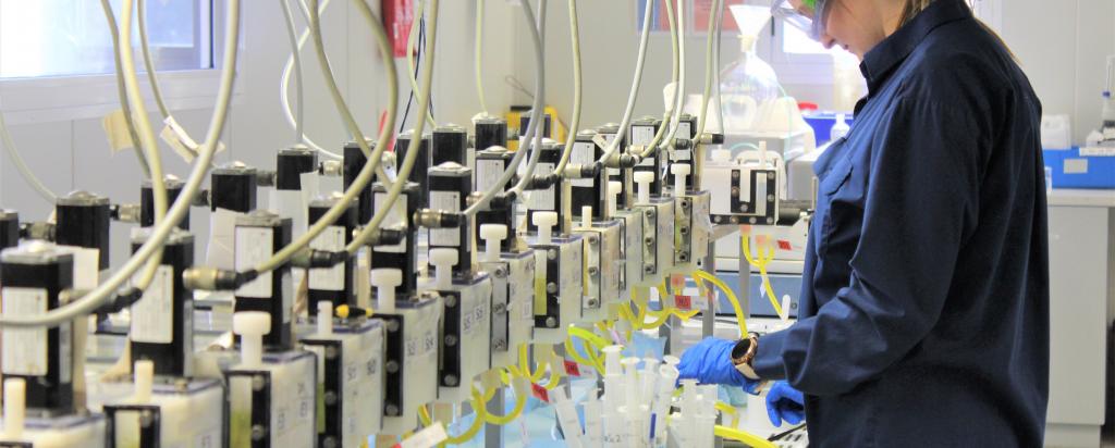 A scientist wearing googles is overseeing experiments in a laboratory.