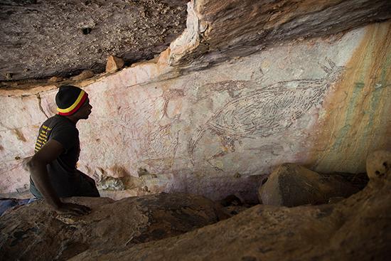 Traditional owner, Ian Waina, contemplating a painting of a kangaroo 