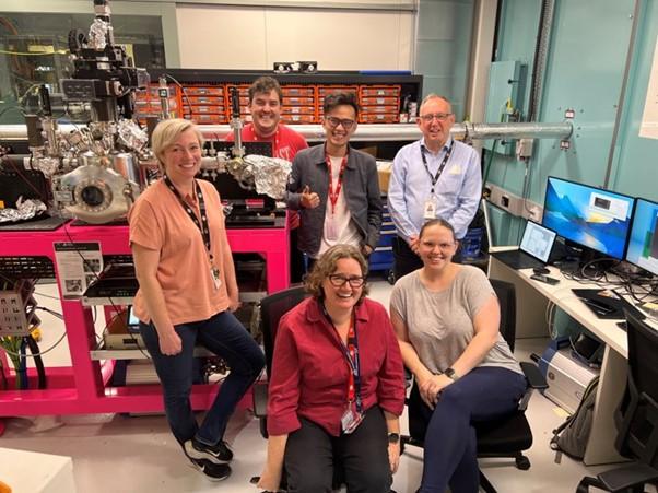 Six people smiling at the camera surrounded by scientific equipment